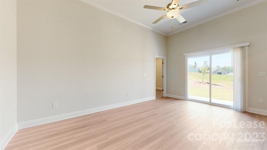 163 Tanner Loop Troutman, NC 28166 - Photo 3 of 27 an empty room with wooden floor fan and windows