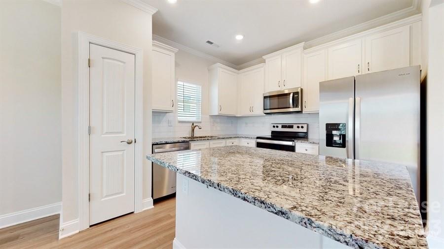 163 Tanner Loop Troutman, NC 28166 - Photo 8 of 27 a kitchen with granite countertop a refrigerator and a sink