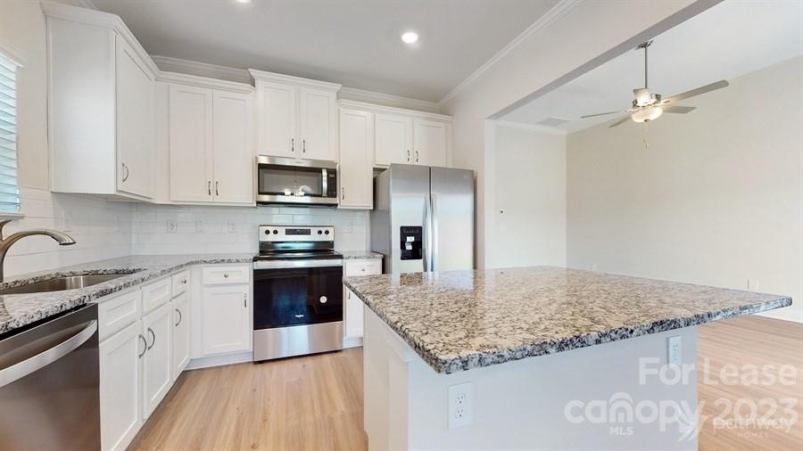 163 Tanner Loop Troutman, NC 28166 - Photo 10 of 27 a kitchen with granite countertop a sink stove and refrigerator