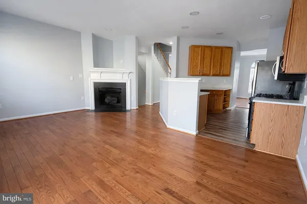 a view of a kitchen and an empty room with wooden floor
