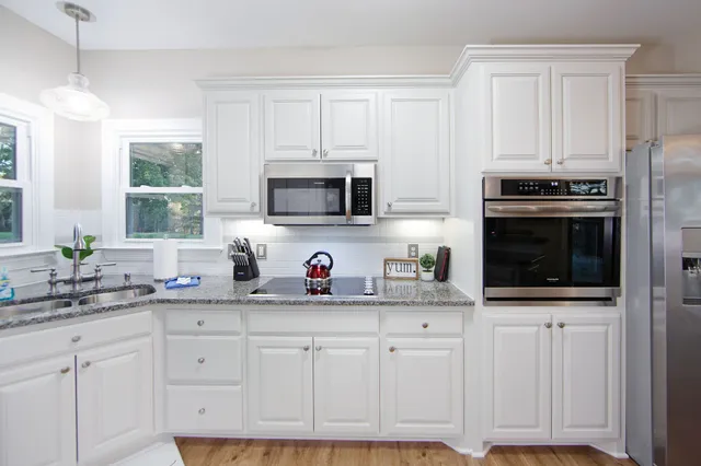 a kitchen with white cabinets and appliances