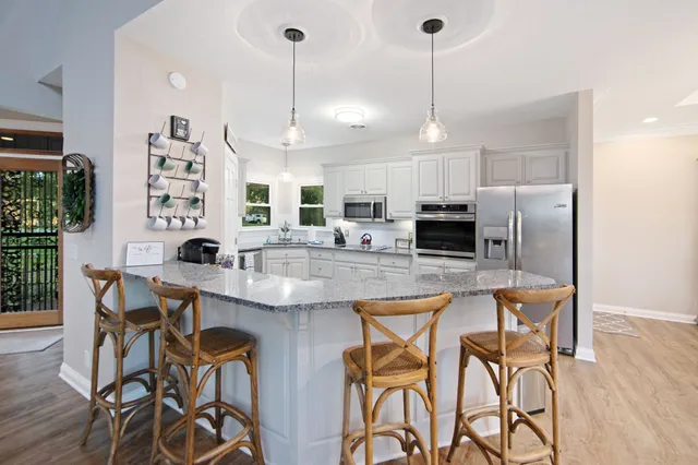 a kitchen with stainless steel appliances kitchen island granite countertop a dining table chairs and sink