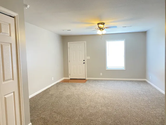 an empty room with a window and a ceiling fan