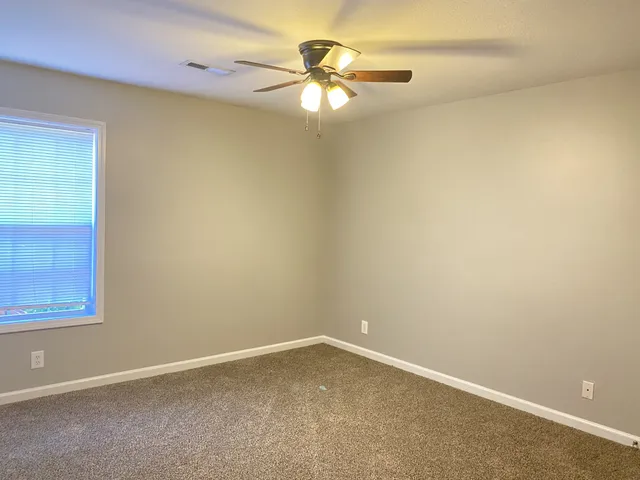 an empty room with a window and a ceiling fan