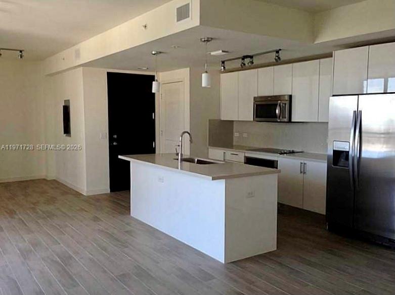 999 Southwest 1st Avenue, Unit 1803 Miami, FL 33130 - Photo 2 of 13 a kitchen with kitchen island white cabinets and stainless steel appliances