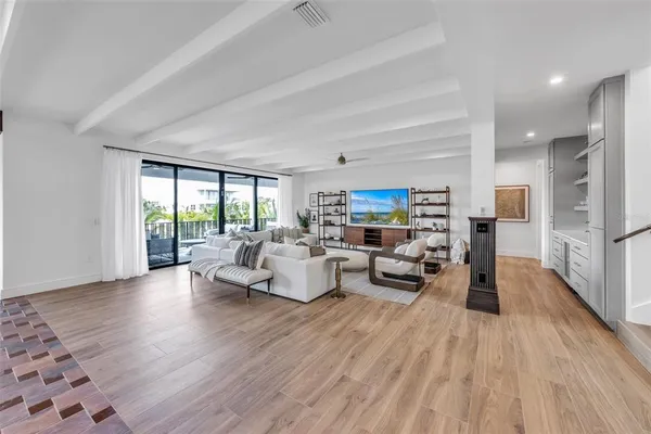 a living room with furniture large windows and wooden floor