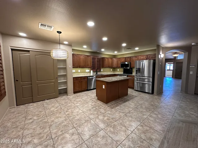 a large kitchen with stainless steel appliances kitchen island granite countertop a refrigerator and a stove top oven