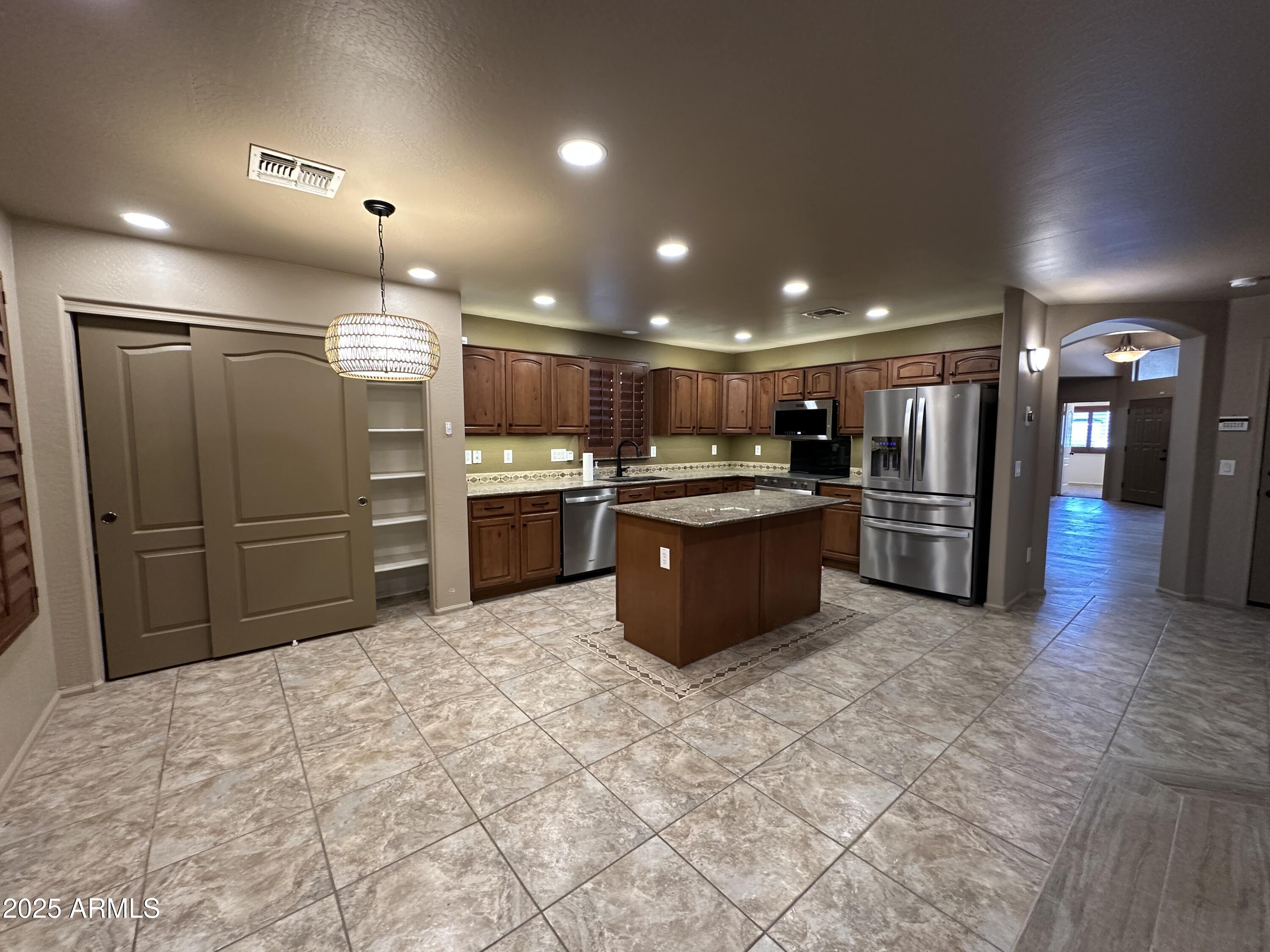 1383 East Kingman Place Casa Grande, AZ 85122 - Photo 5 of 18 a large kitchen with stainless steel appliances kitchen island granite countertop a refrigerator and a stove top oven
