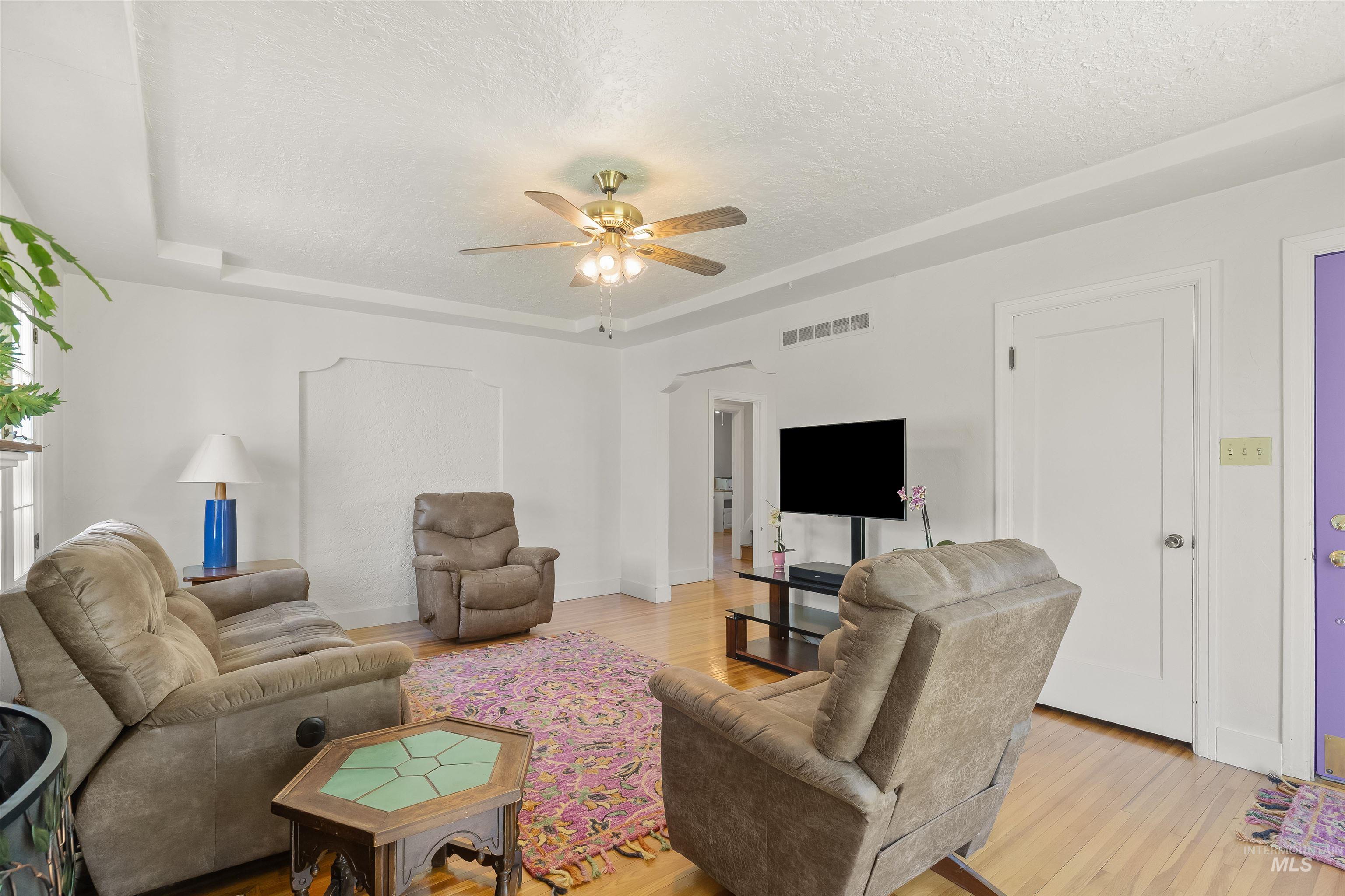 924 N Street Lewiston, ID 83501 - Photo 10 of 46 Living space featuring hardwood flooring, a ceiling fan with integrated lighting, tray ceiling details, an arched wall niche, and white interior doors
