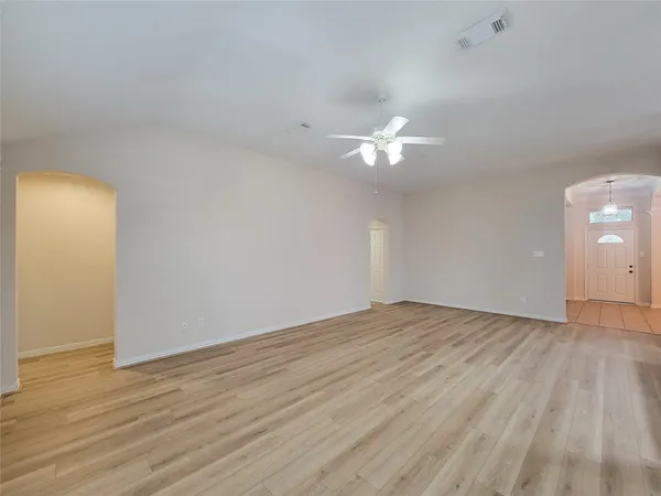 a view of an empty room with window and chandelier fan