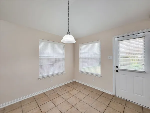 a view of an empty room with window and chandelier fan