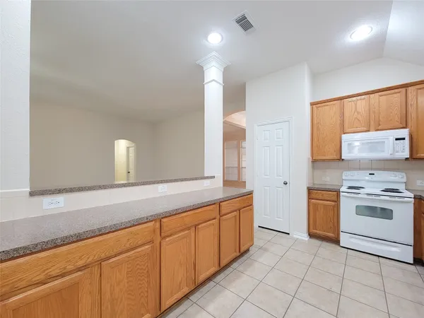 a large kitchen with granite countertop a sink a counter space and cabinets