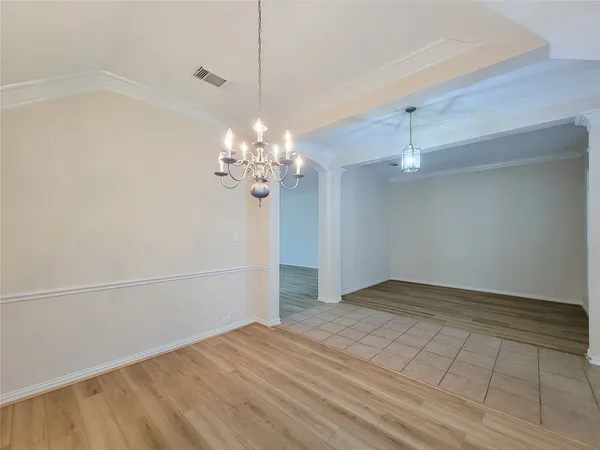 a view of an empty room with a chandelier fan