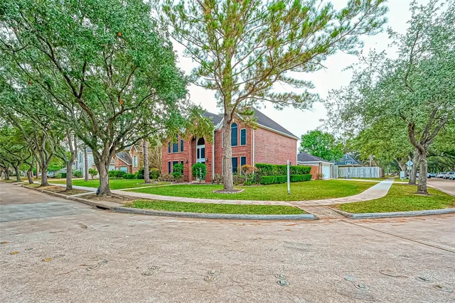 a view of a big house with a big yard and large trees