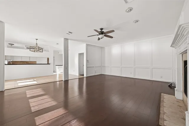 a view of an empty room with kitchen and window