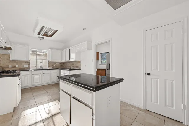a kitchen with granite countertop white cabinets white appliances and a sink
