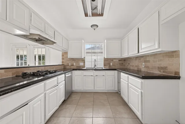 an empty room with wooden floor chandelier fan and windows