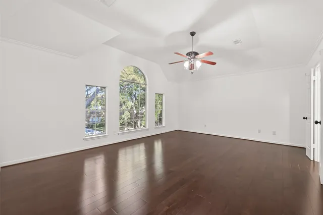 an empty room with a chandelier fan and windows
