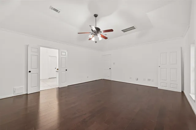an empty room with chandelier fan and windows