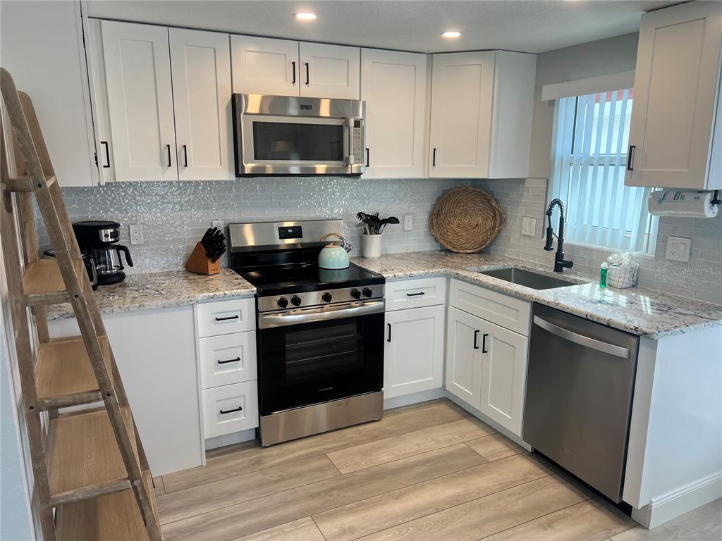 6154 Midnight Pass Road, Unit D02 Sarasota, FL 34242 - Photo 4 of 12 a kitchen with granite countertop a sink and steel appliances