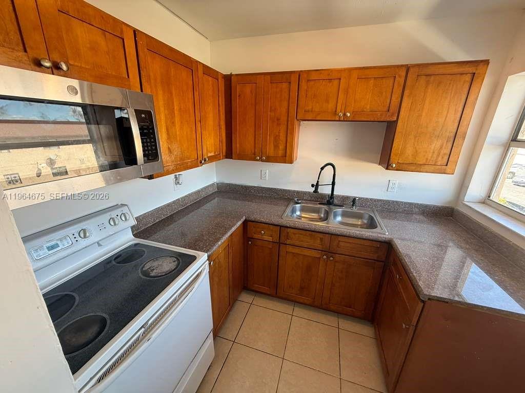 5491 West 24th Avenue, Unit 39 Hialeah, FL 33016 - Photo 10 of 12 a kitchen with a sink stove and cabinets