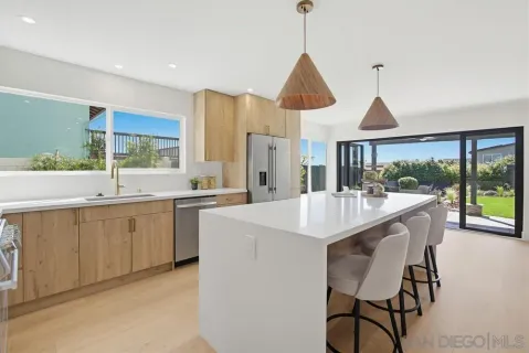 a kitchen with stainless steel appliances a sink a stove and white cabinets next to a large window