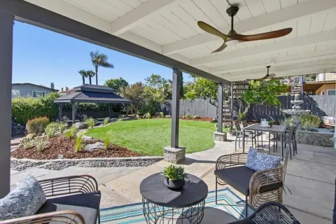 a view of a patio with a dining table chairs and a floor to ceiling window