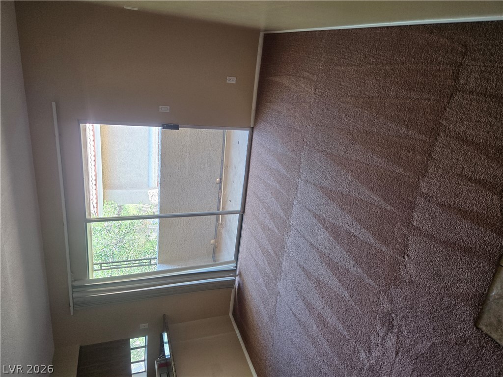 7200 West Pirates Cove Road, Unit 2047 Las Vegas, NV 89145 - Photo 10 of 17 A sliding glass door opens to a balcony, bringing in natural light to the carpeted interior.