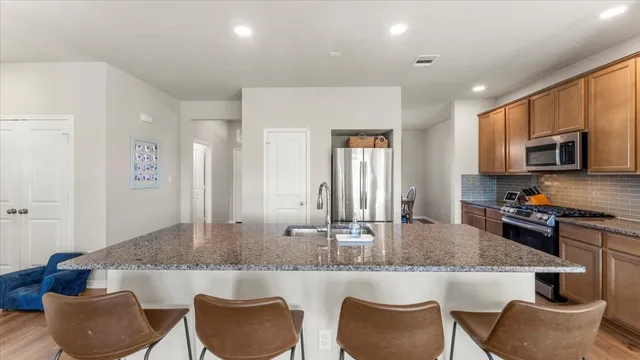 a kitchen with granite countertop kitchen island stainless steel appliances a sink and a refrigerator