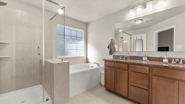 a bathroom with a double vanity sink mirror and bathtub