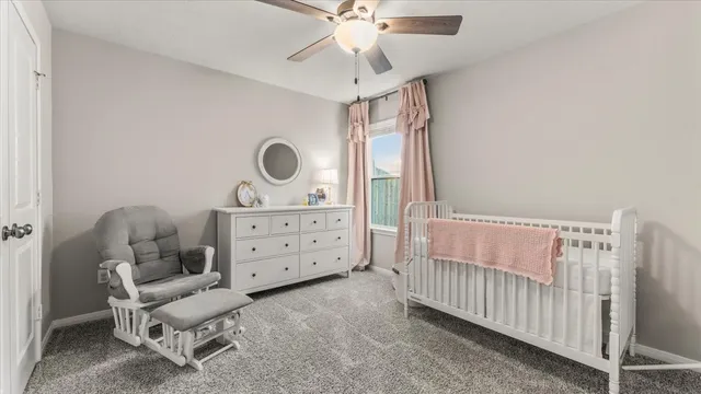 a bedroom with a baby bed a chandelier and a window