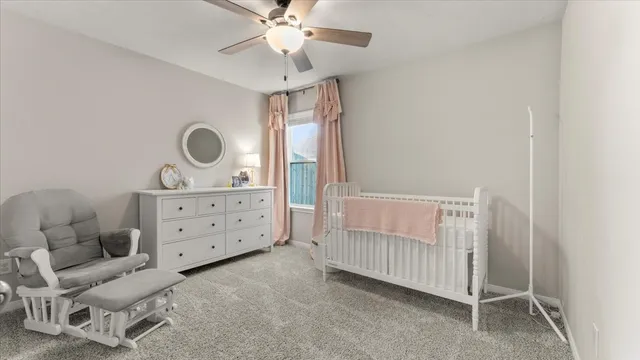 a bedroom with a baby bed a chandelier with a dresser and a window