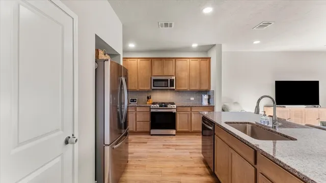 a kitchen with stainless steel appliances granite countertop a sink stove and refrigerator