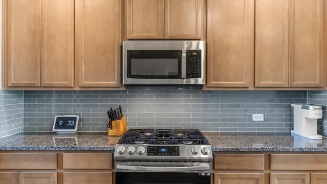 a kitchen with granite countertop stainless steel appliances white cabinets granite counter tops and a wooden floors