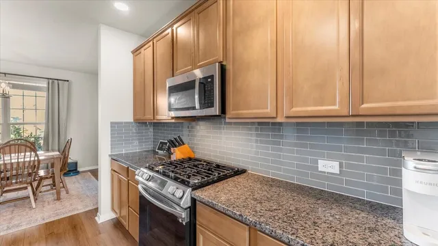 a kitchen with stainless steel appliances granite countertop a stove a sink and a microwave
