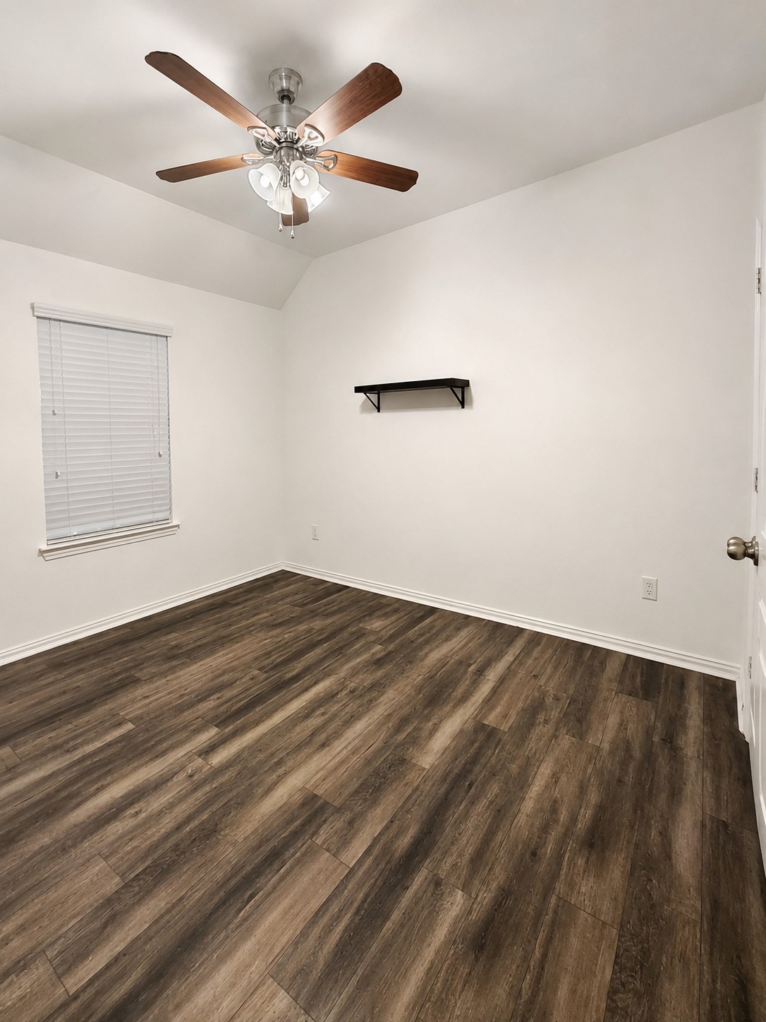 349 Razzmatazz Trail Buda, TX 78610 - Photo 10 of 27 A well-lit room offers vaulted ceilings and rich wood-style flooring.