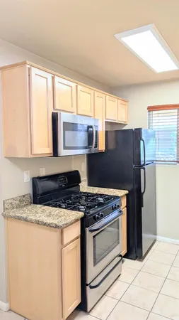 a kitchen with granite countertop a stove cabinets and refrigerator