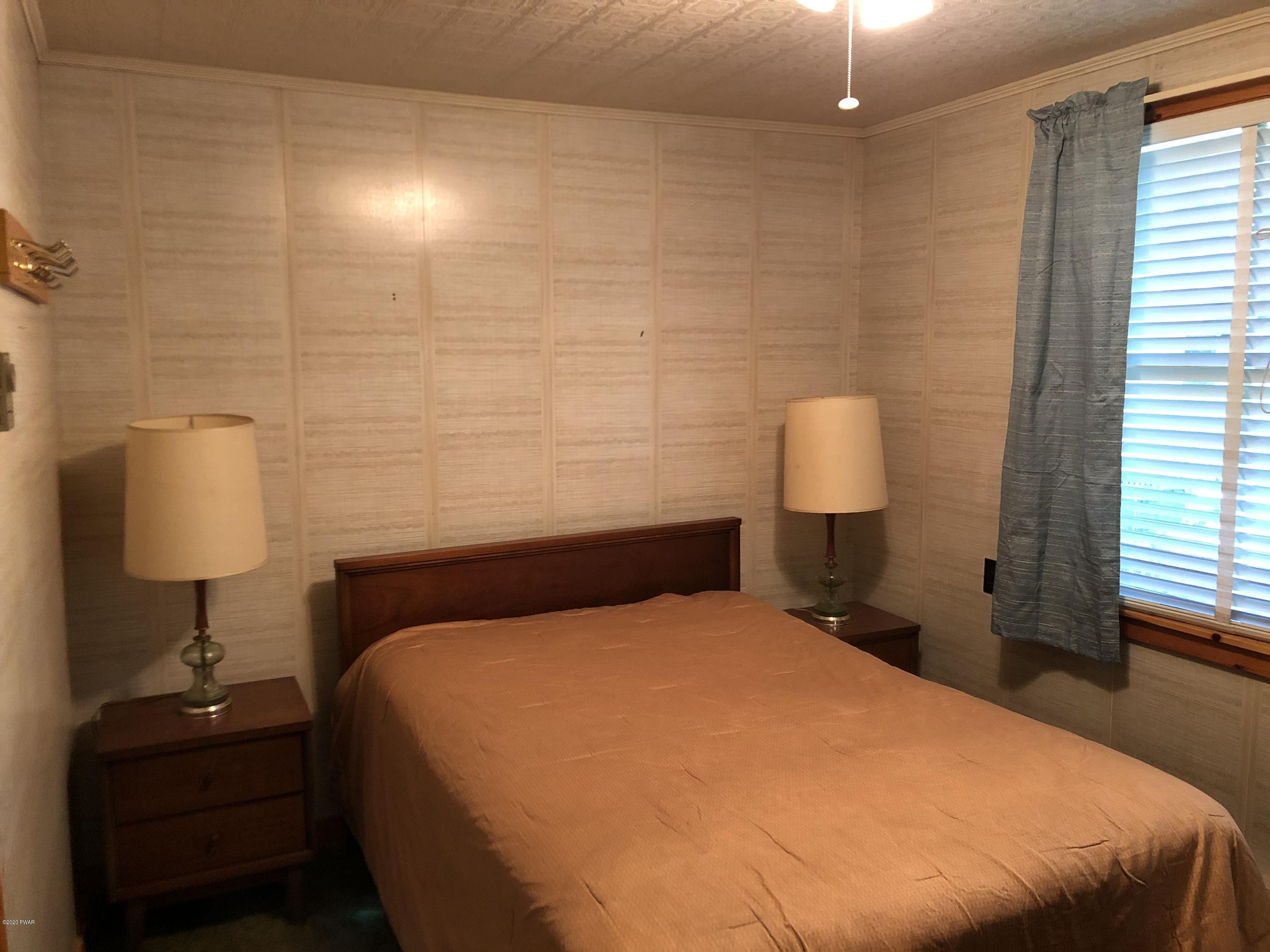 45 W Road Hawley, PA 18428 - Photo 9 of 19 a bedroom with a bed and a lamp on table