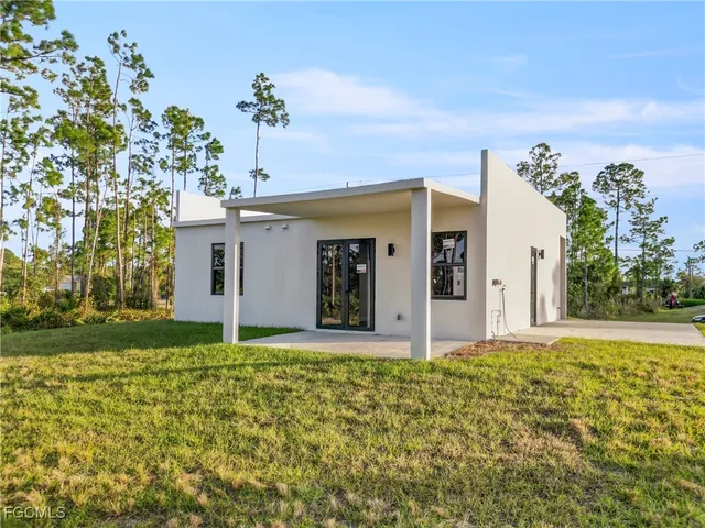 a view of a house with a big yard and large tree
