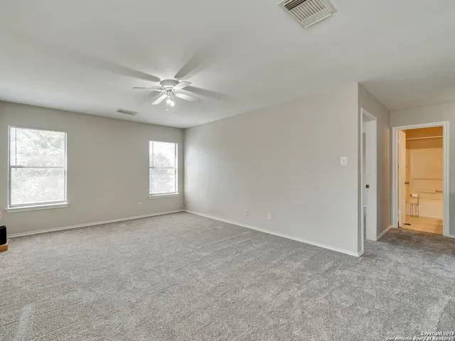 an empty room with windows and fan