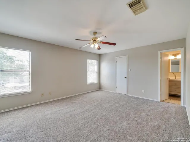 an empty room with windows and ceiling fan
