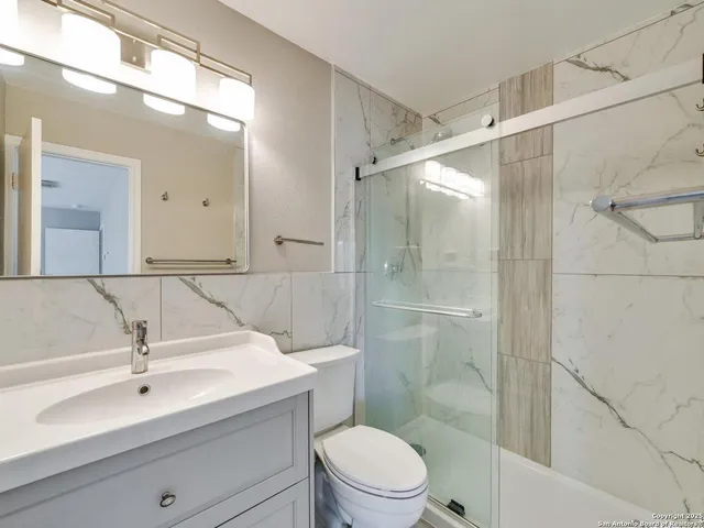 a bathroom with a sink a mirror a toilet and shower