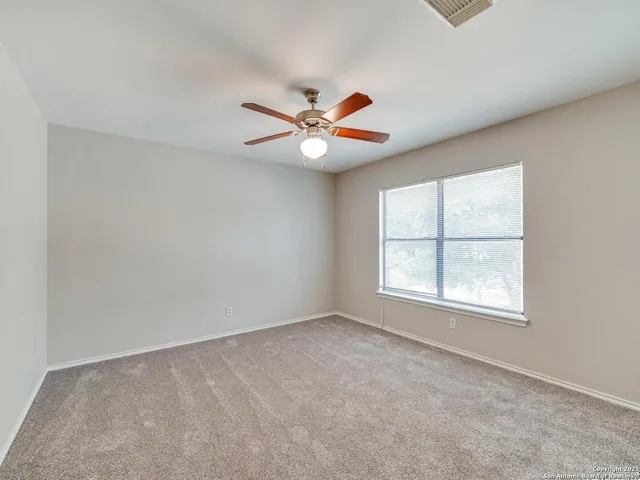 an empty room with chandelier fan and windows