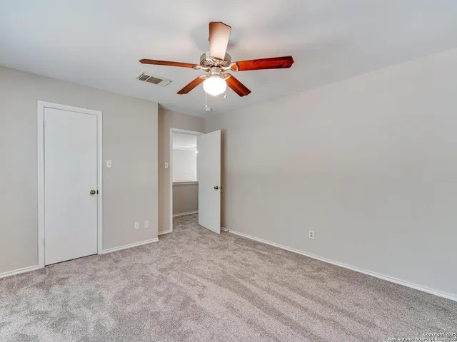 an empty room with closet and a chandelier fan