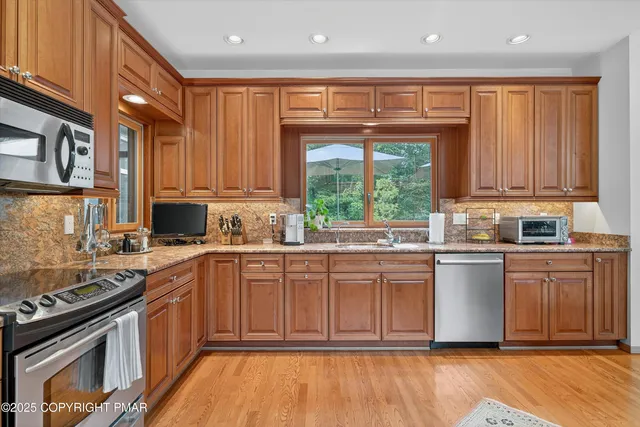 a utility room with stainless steel appliances granite countertop a stove and a window