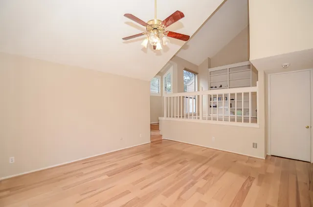 a view of an empty room with window and a chandelier fan