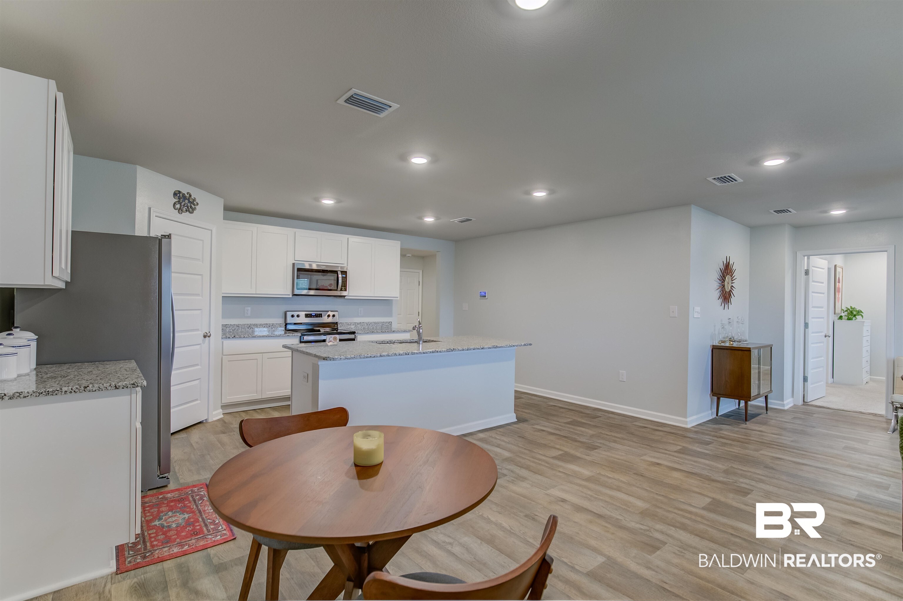 8033 Irwin Loop Daphne, AL 36526 - Photo 20 of 38 Open-concept living space featuring wood-finish flooring, recessed lighting, and a kitchen with white cabinetry