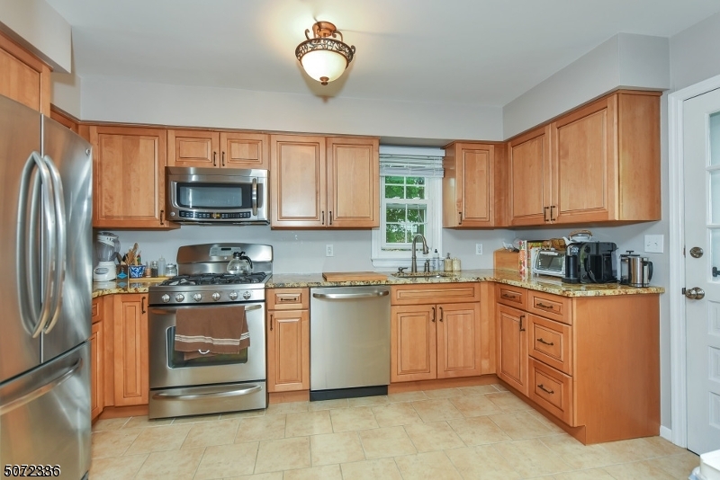 42 Walnut Street, Unit 1 Montclair, NJ 07042 - Photo 7 of 11 a kitchen with stainless steel appliances granite countertop a stove top oven a sink dishwasher and a refrigerator with wooden cabinets