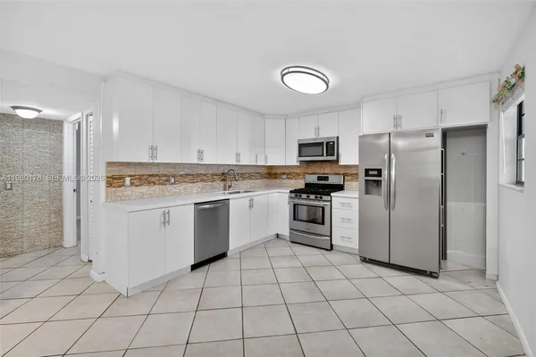 a kitchen with white cabinets stainless steel appliances and a sink