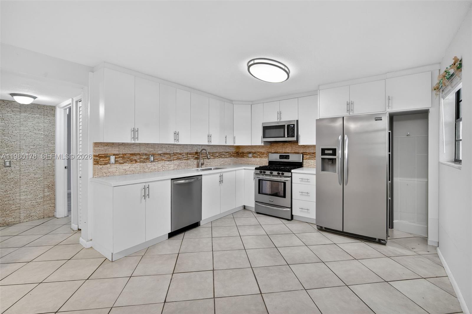 3265 Virginia Street, Unit 9 Miami, FL 33133 - Photo 13 of 32 a kitchen with white cabinets stainless steel appliances and a sink